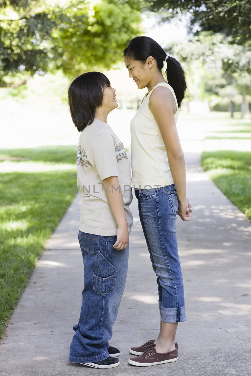 Asian Brother and Sister Standing in a Park Looking at each Other