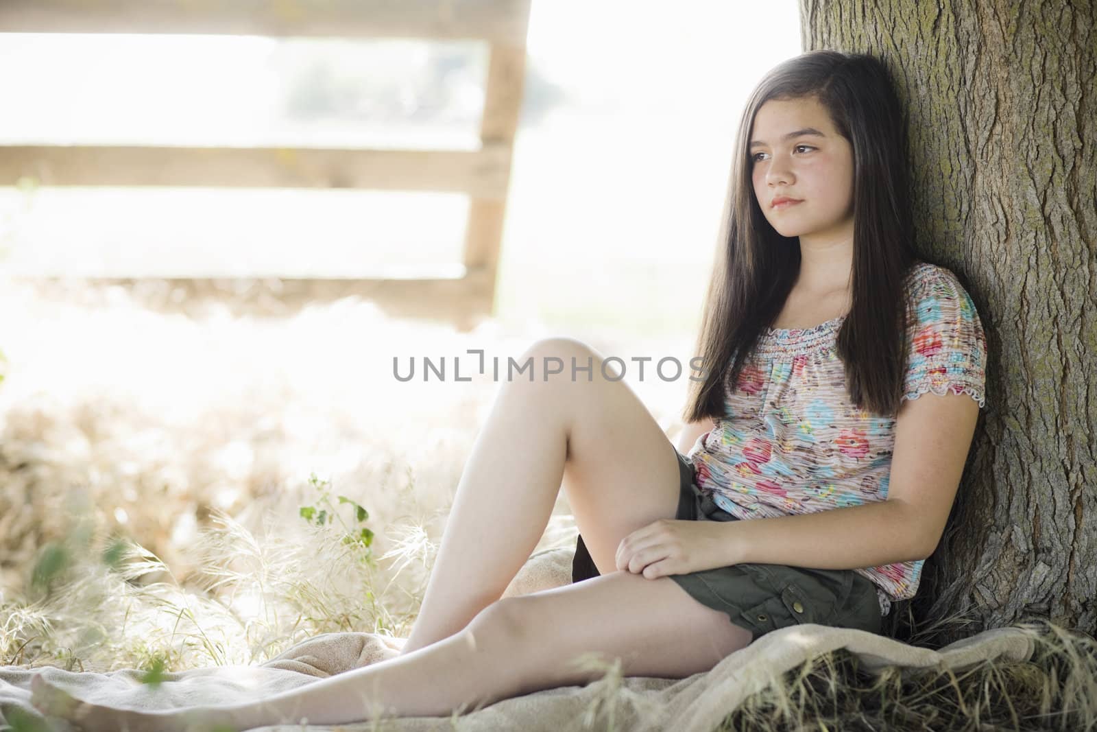 Young Girl Sitting on a Blanket Under Tree