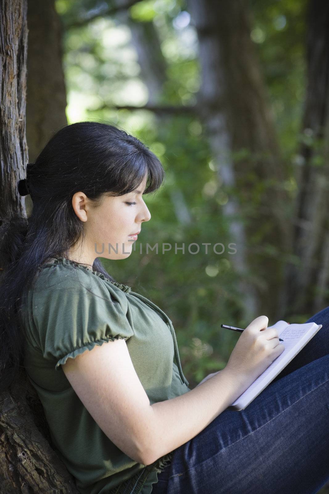 Young Woman Sitting in Woods Writing in Journal