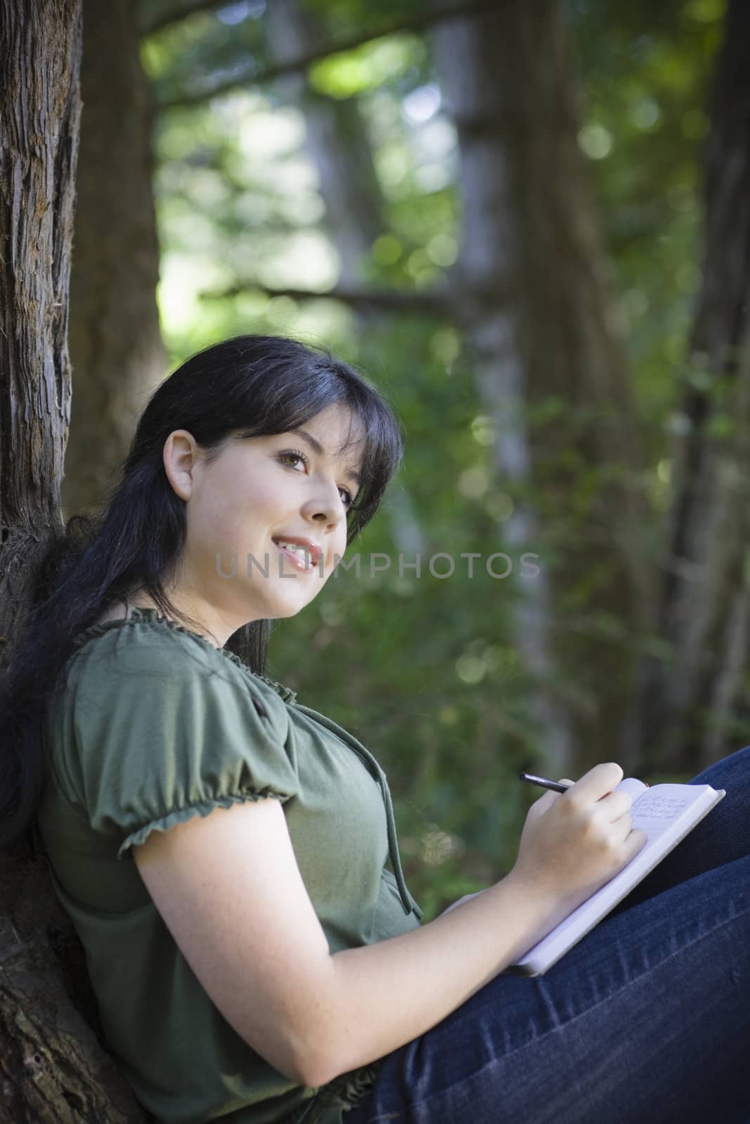Young Woman In Woods Writing in Journal Looking Away from Camera