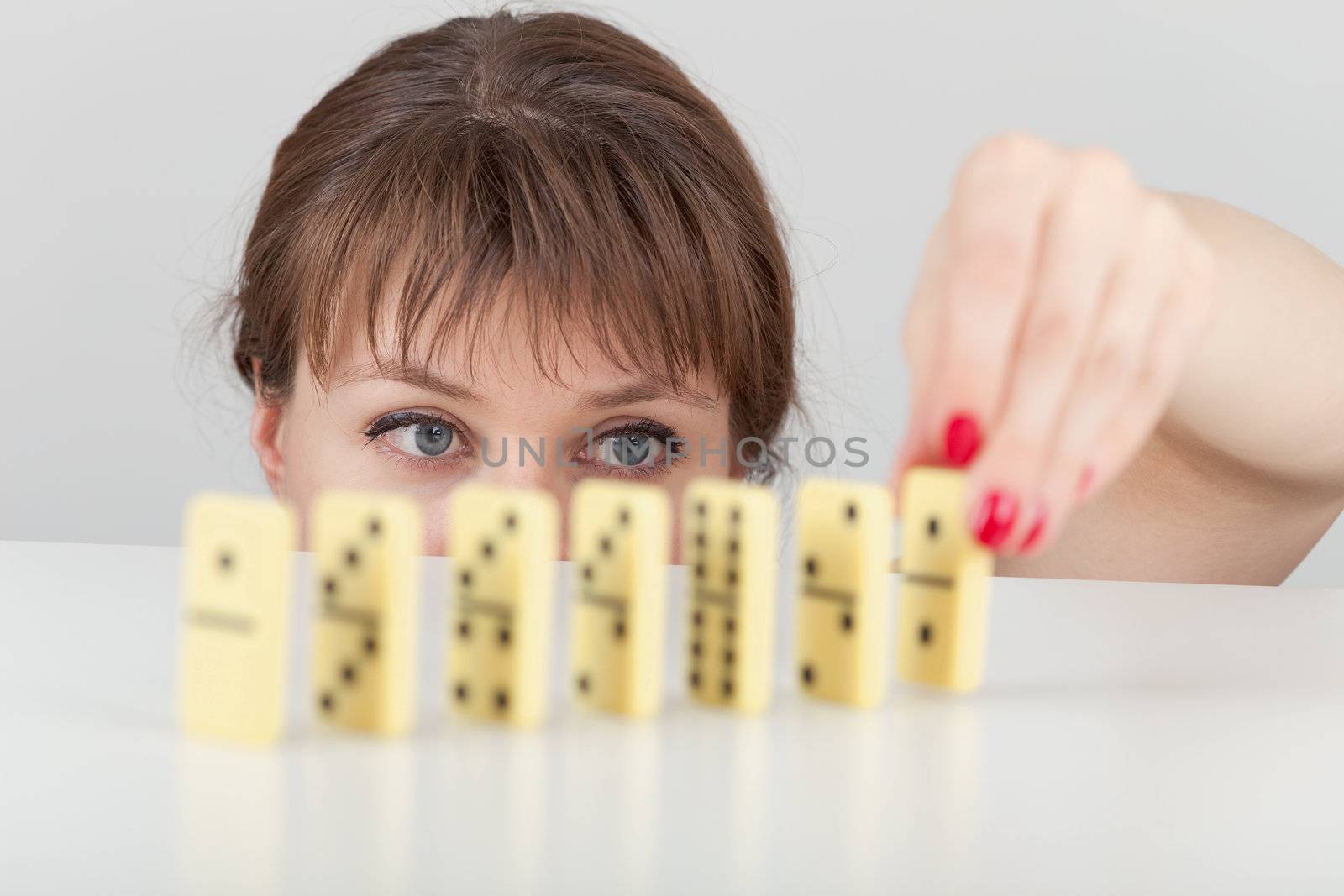 The girl builds a line of dominoes counters close up