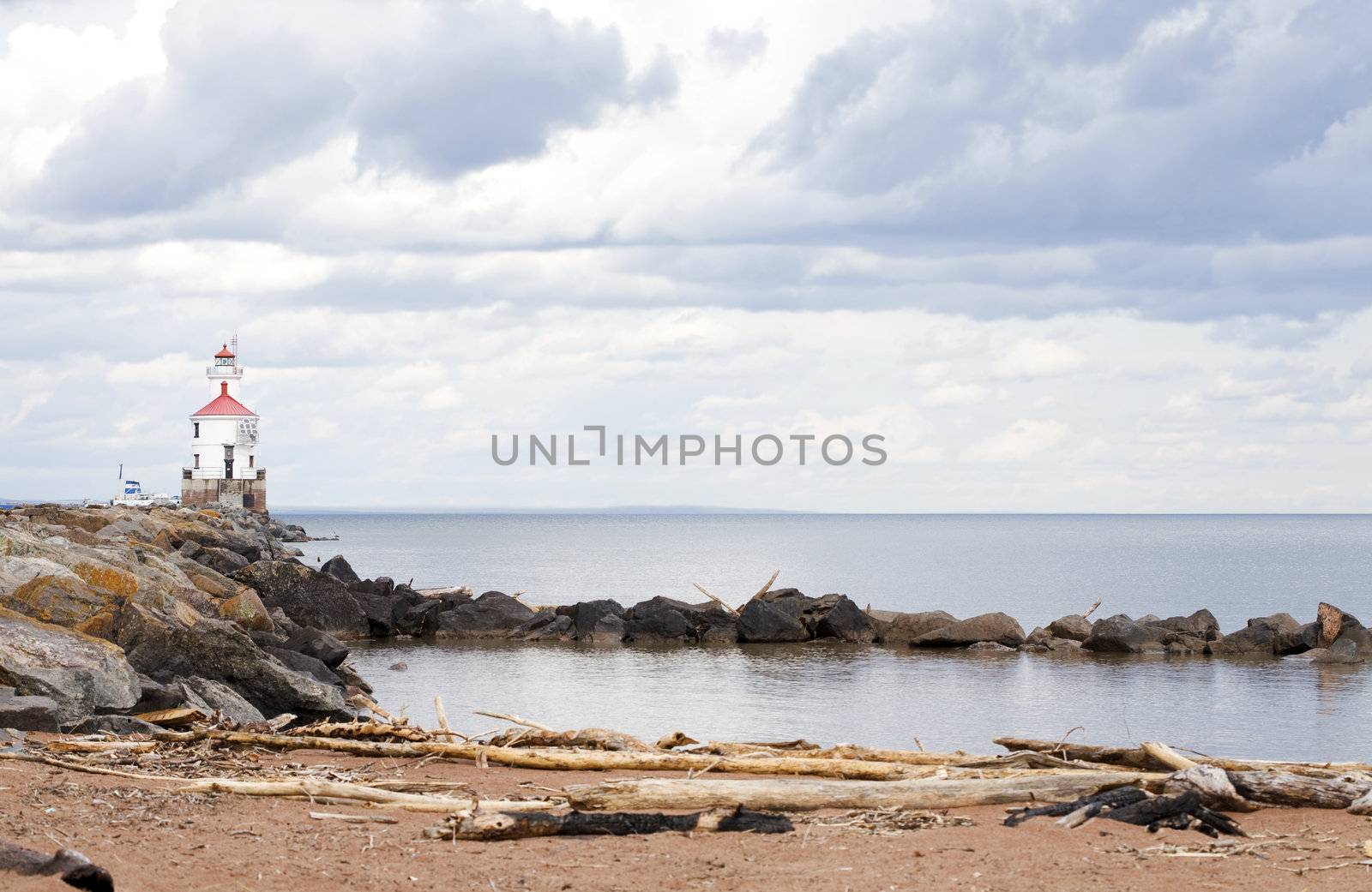 Lighthouse at end of rocky pier along Lake Superior by jarenwicklund