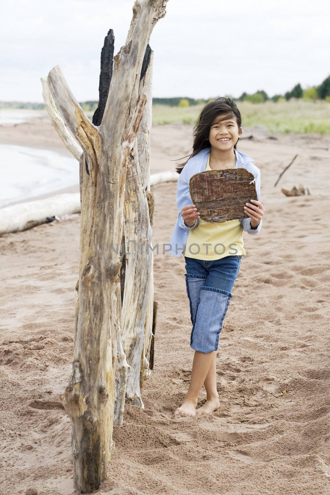 Little girl on beach holding up blank wooden sign