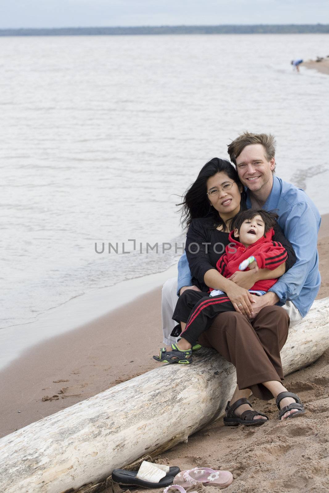 Biracial husband and wife holding their toddler at the beach