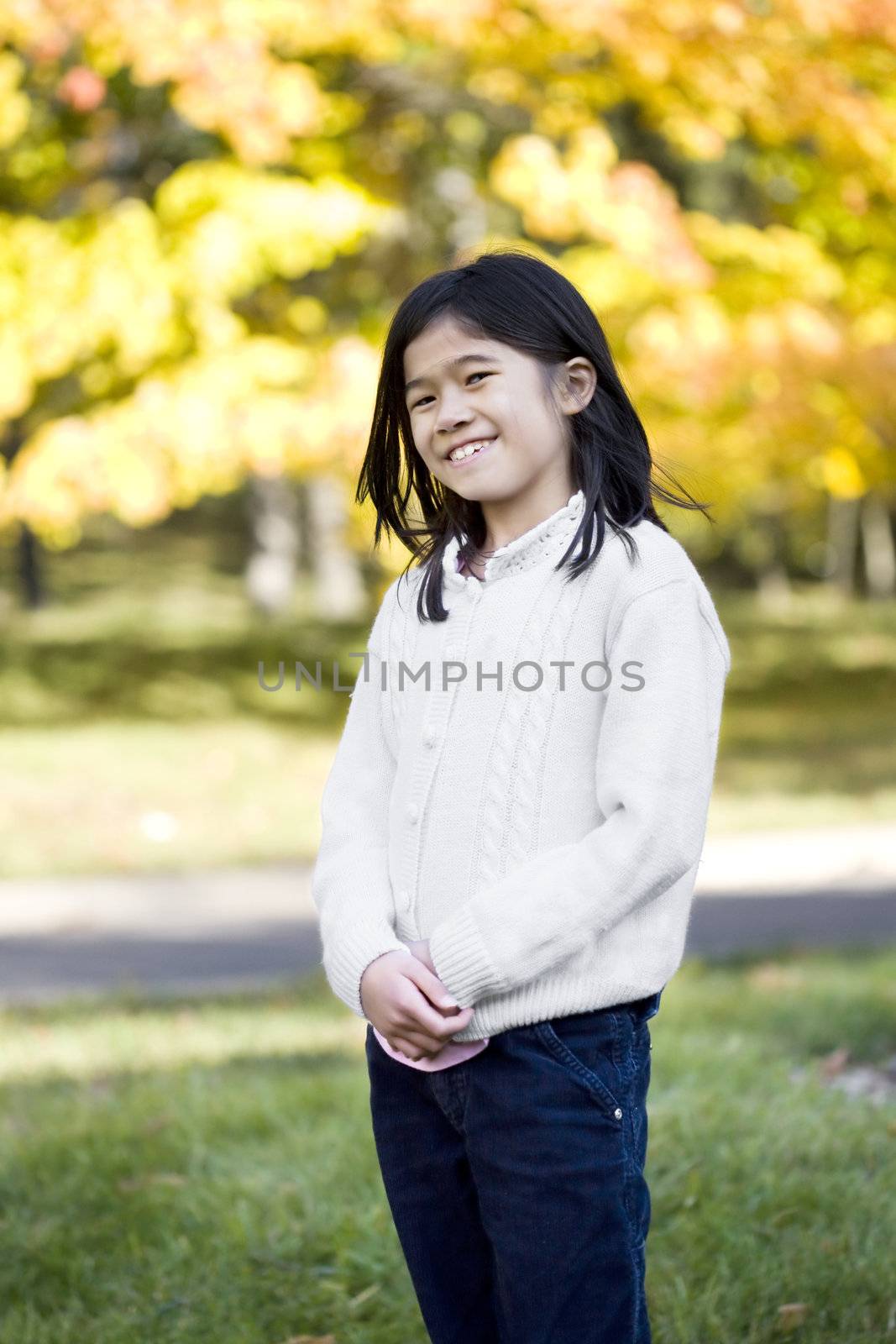 young girl standing against background of colorful autumn leaves