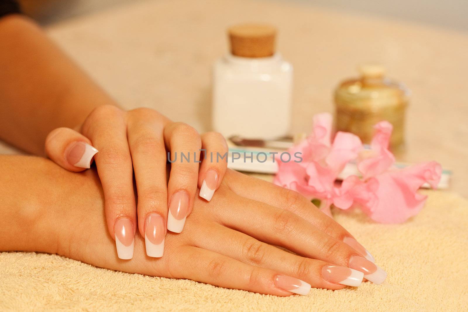 Hands of young woman with french manicure on the towel