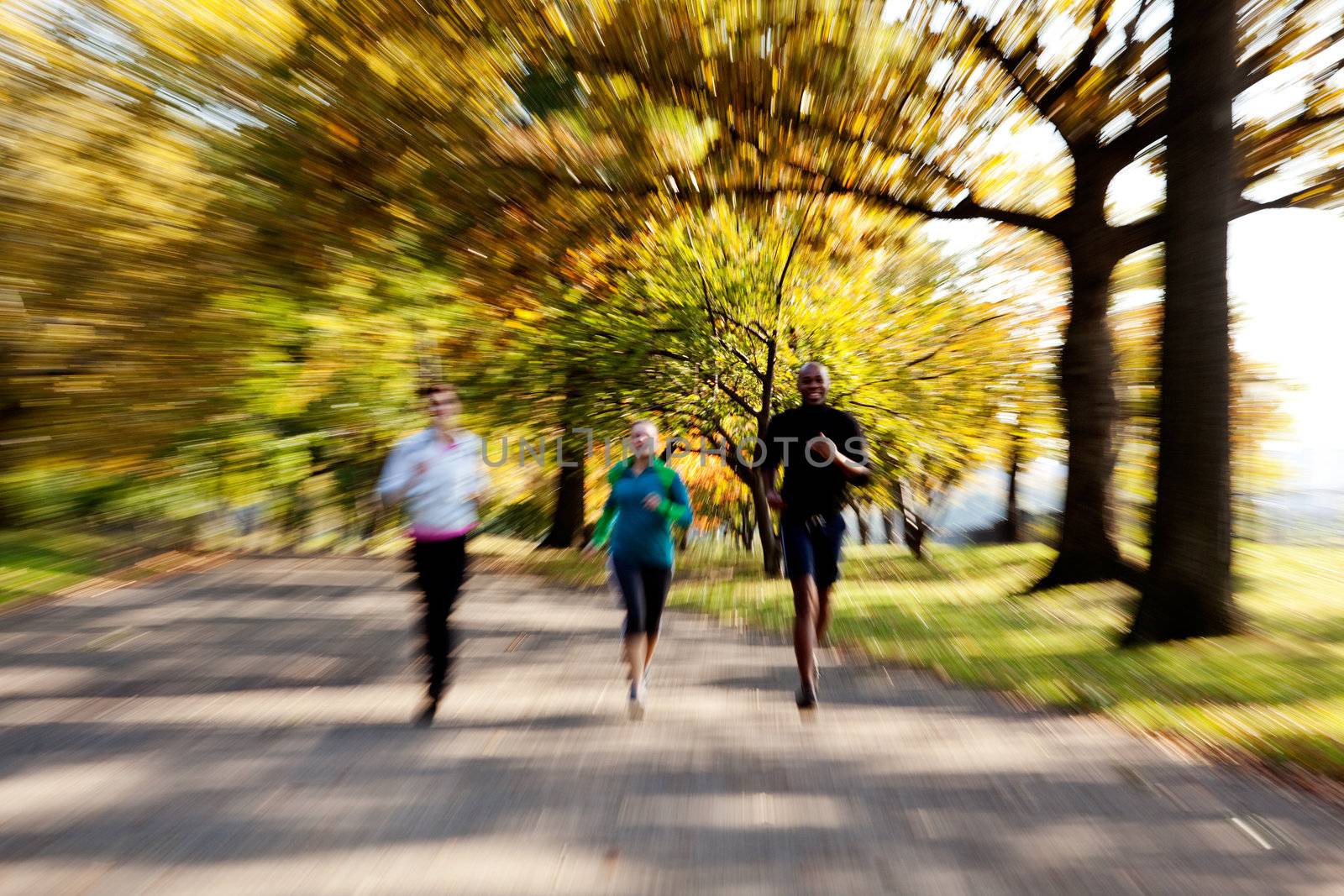 Three people jogging in the park with zoom blur