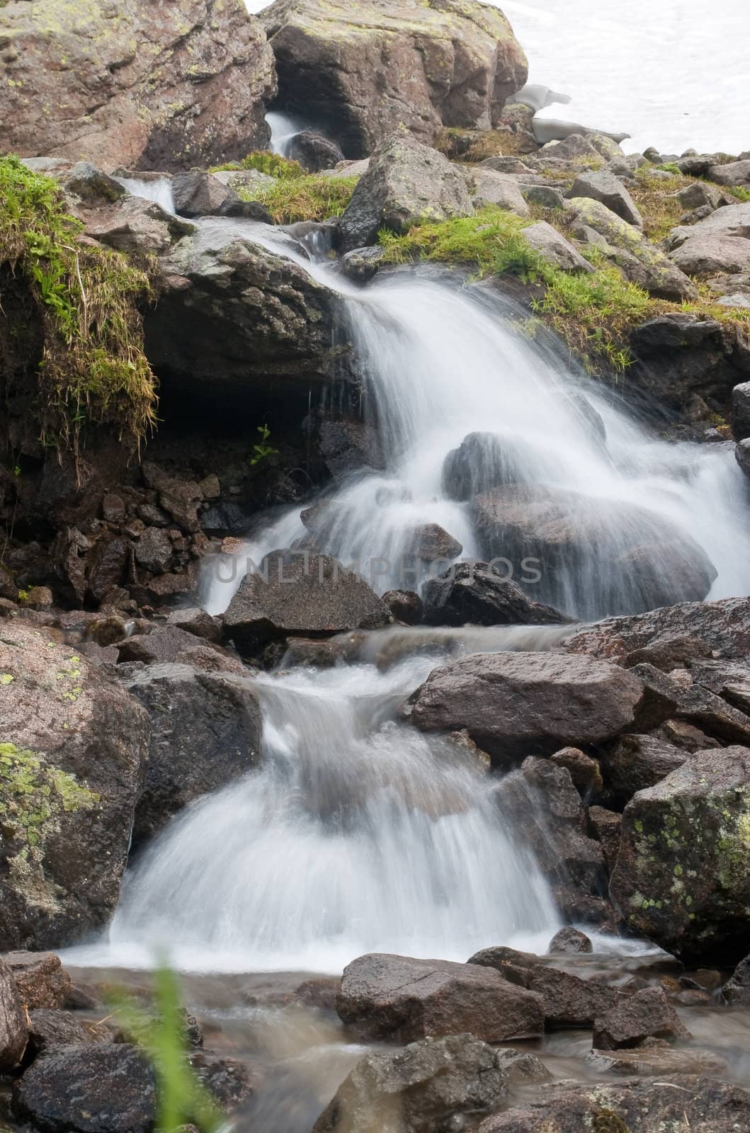 water's flowing from glacier with little cascades in Italian alps