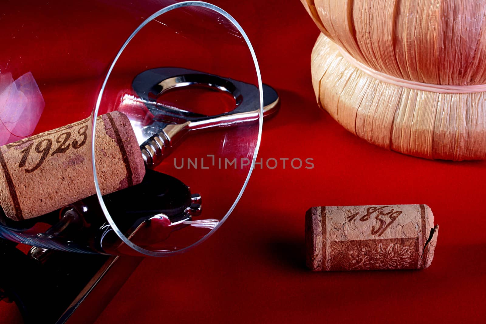 Stoppers from bottles with wine on a red fabric with a glass and a corkscrew.