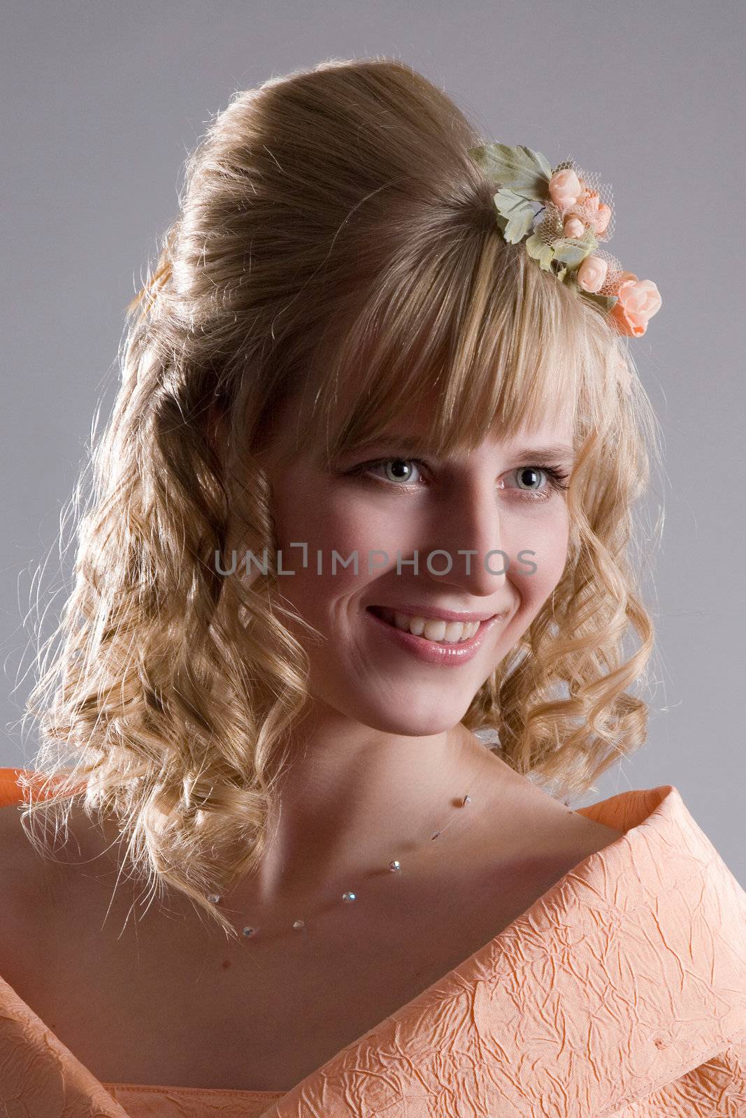 Beautiful bride in cream dress with charming smile and cream-colour flower in her hair.
