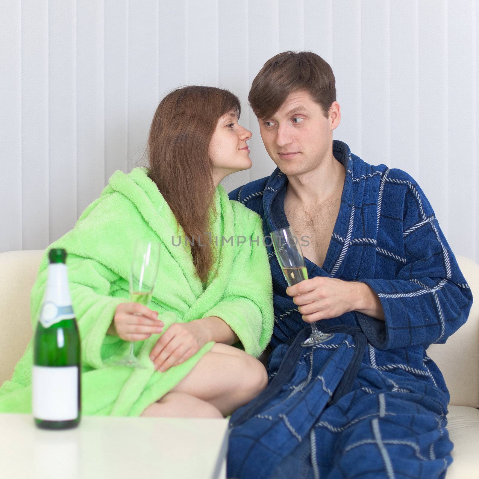 The guy and the girl drink  champagne wine on a sofa