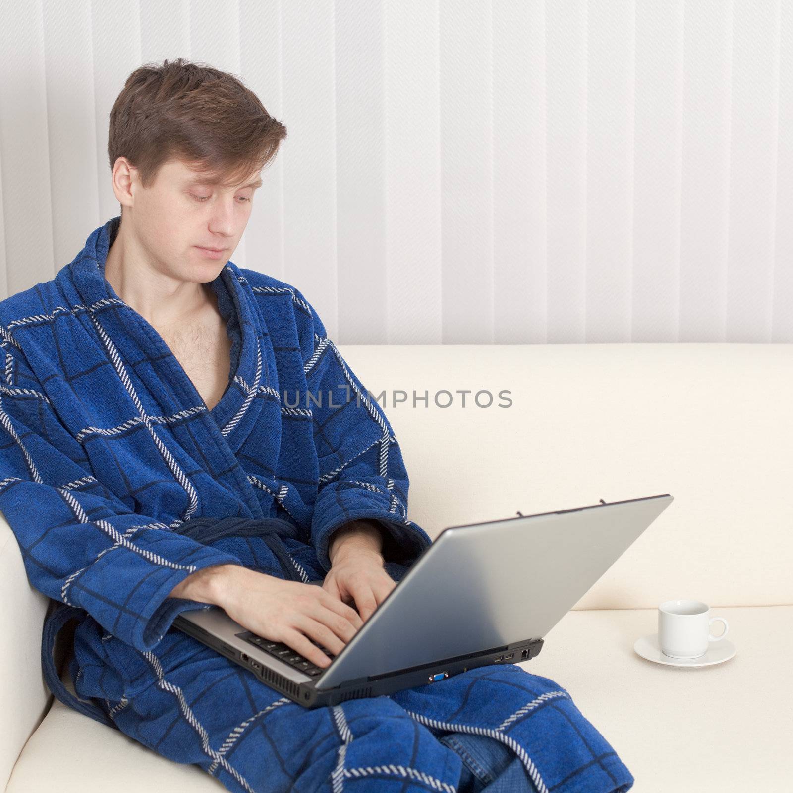 The young man in dressing gown with the laptop