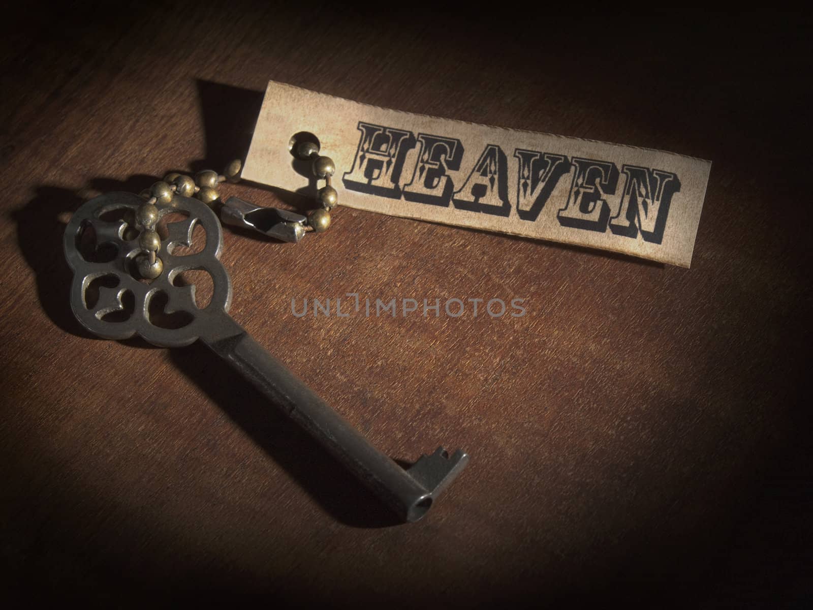 An old key attached to a label saying HEAVEN over a wooden table.