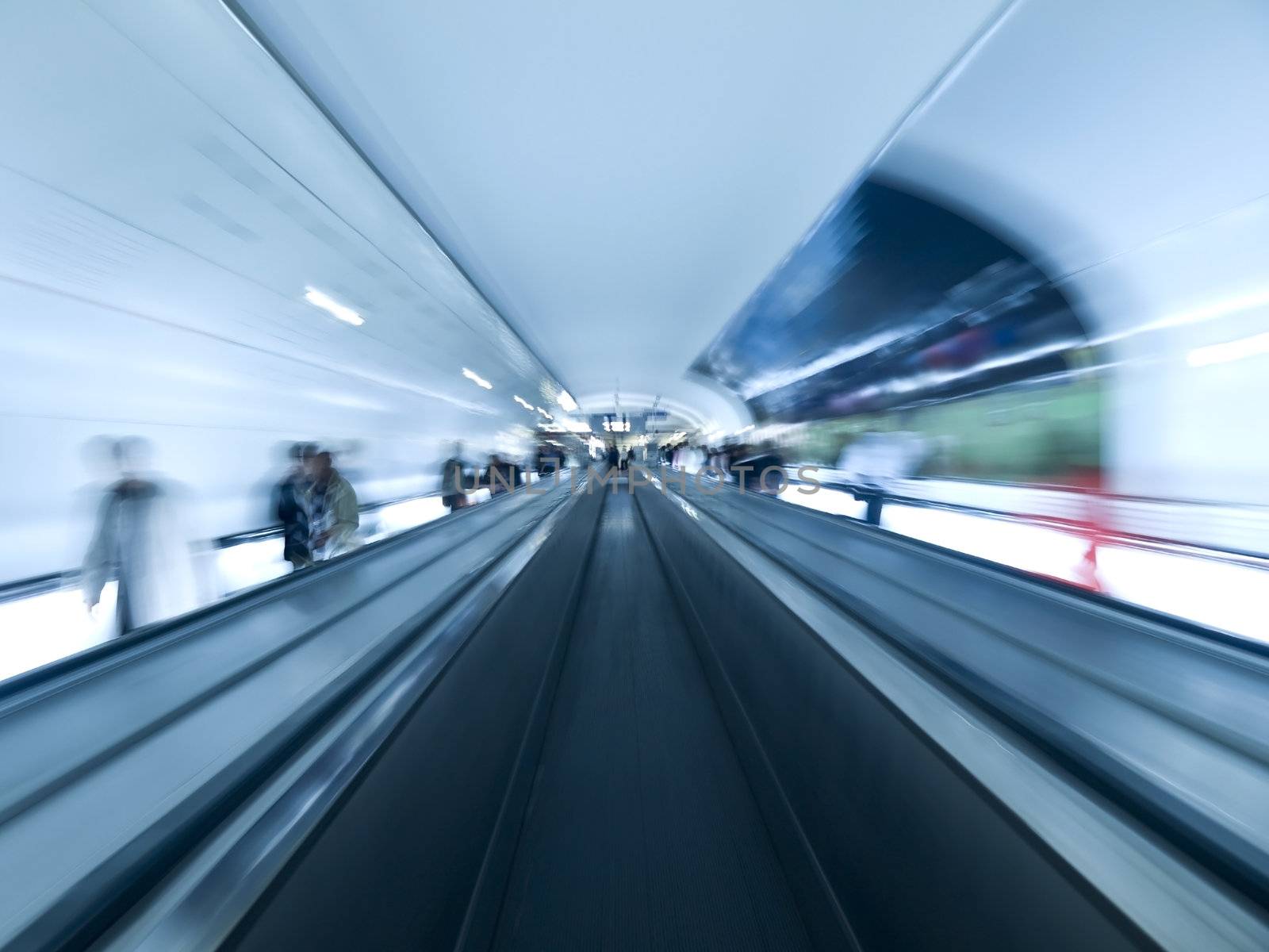 Futuristic image. Blurred people on the walkway tunnel. Empty center lane.