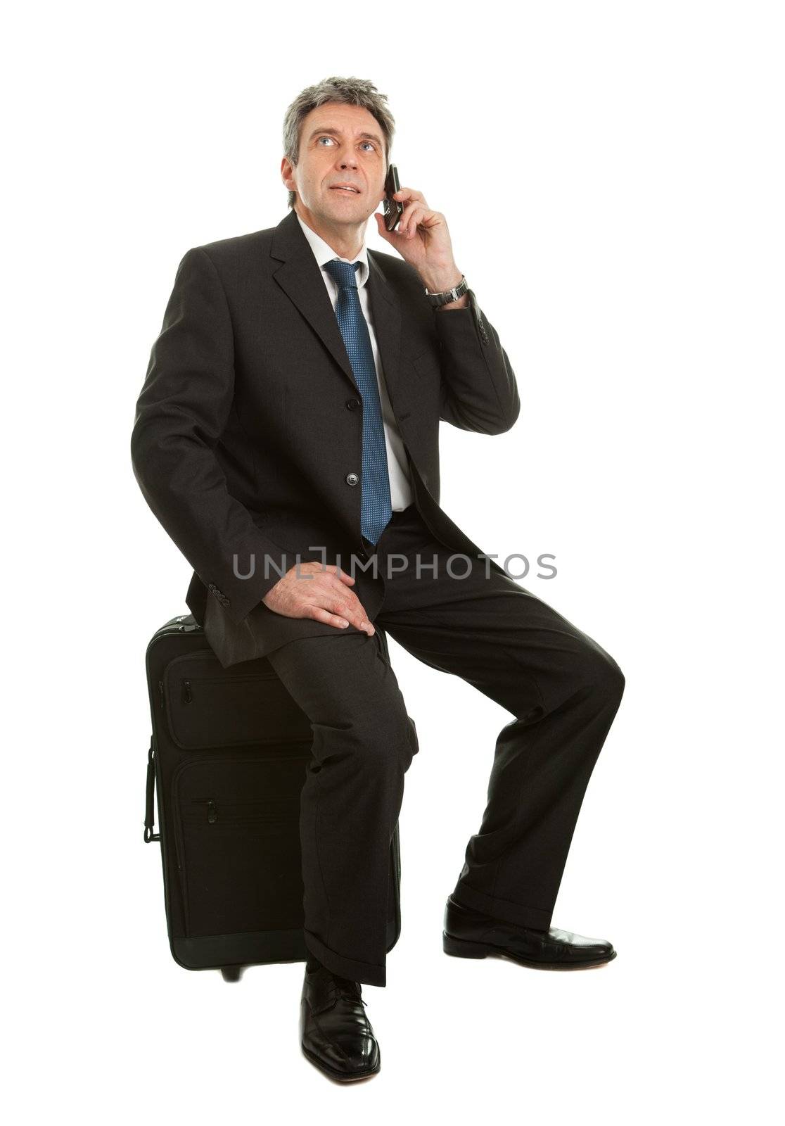 Senior businessmen sitting on travel bag and talking on cellphone. Isoalted on white