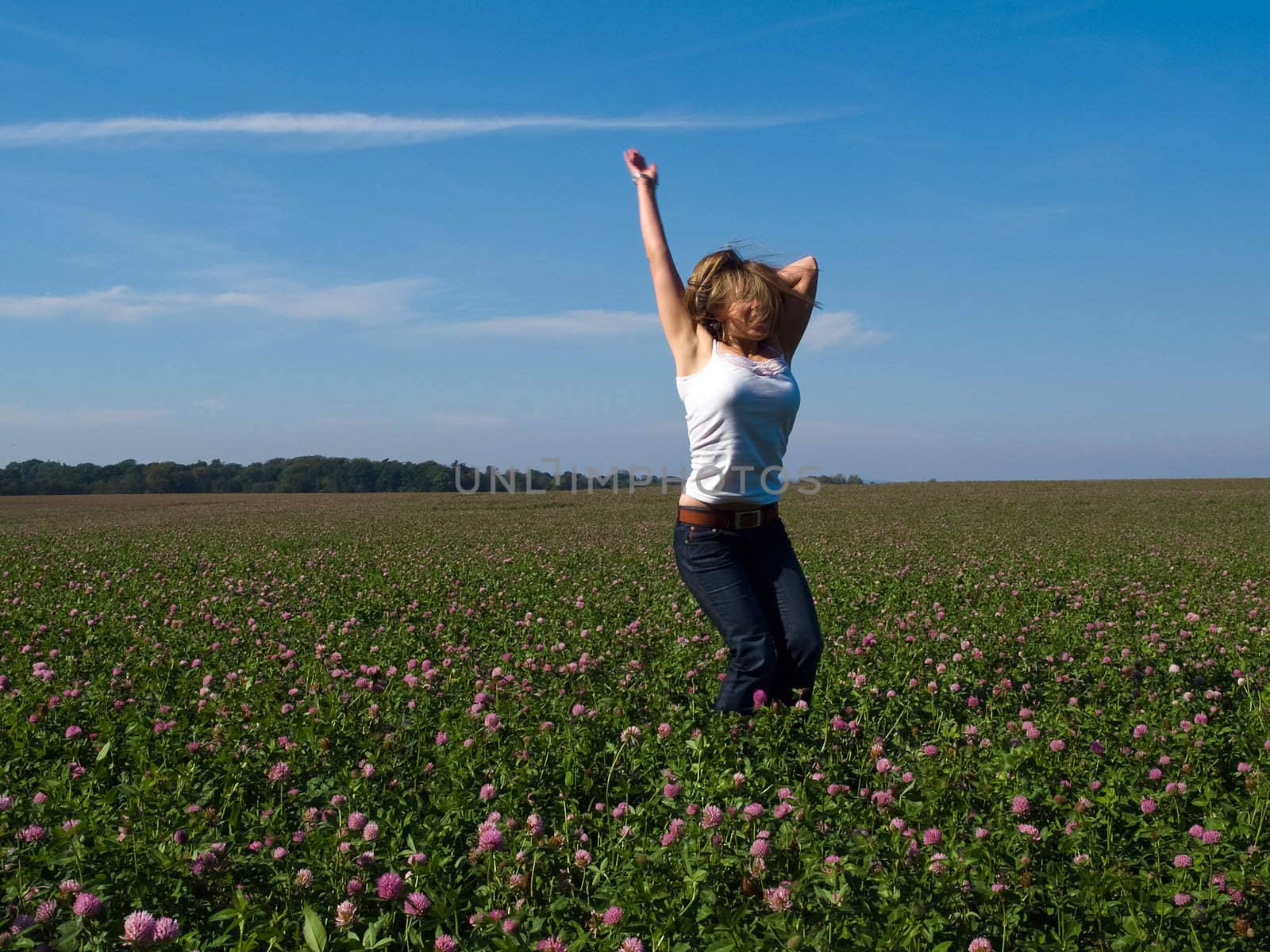 Beautiful attractive young happy woman girl jumping in a sunny flowers field