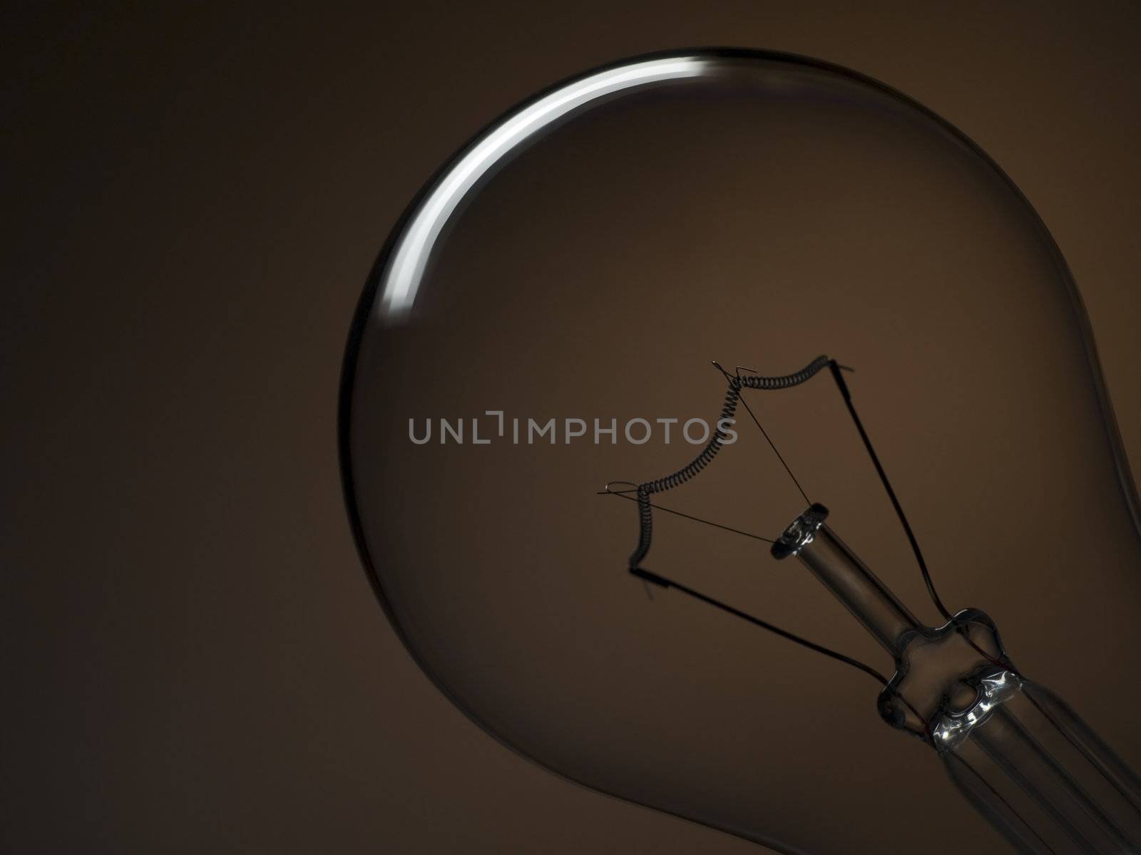 Close up on a transparent light bulb over a brown background.