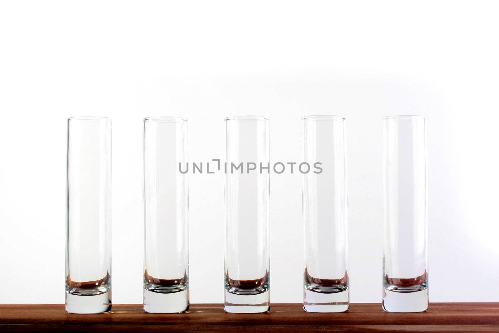 Five empty high narrow glasses on white background