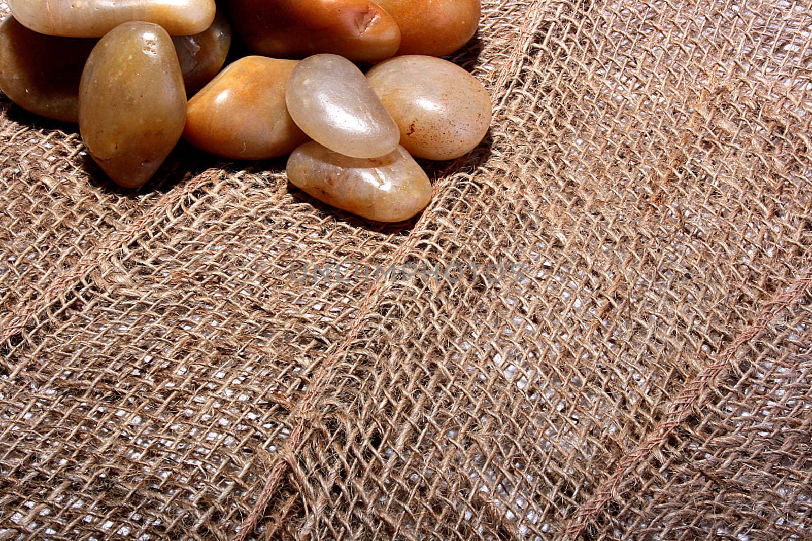 Sea stones lie on a rough sackcloth is light brown colour.