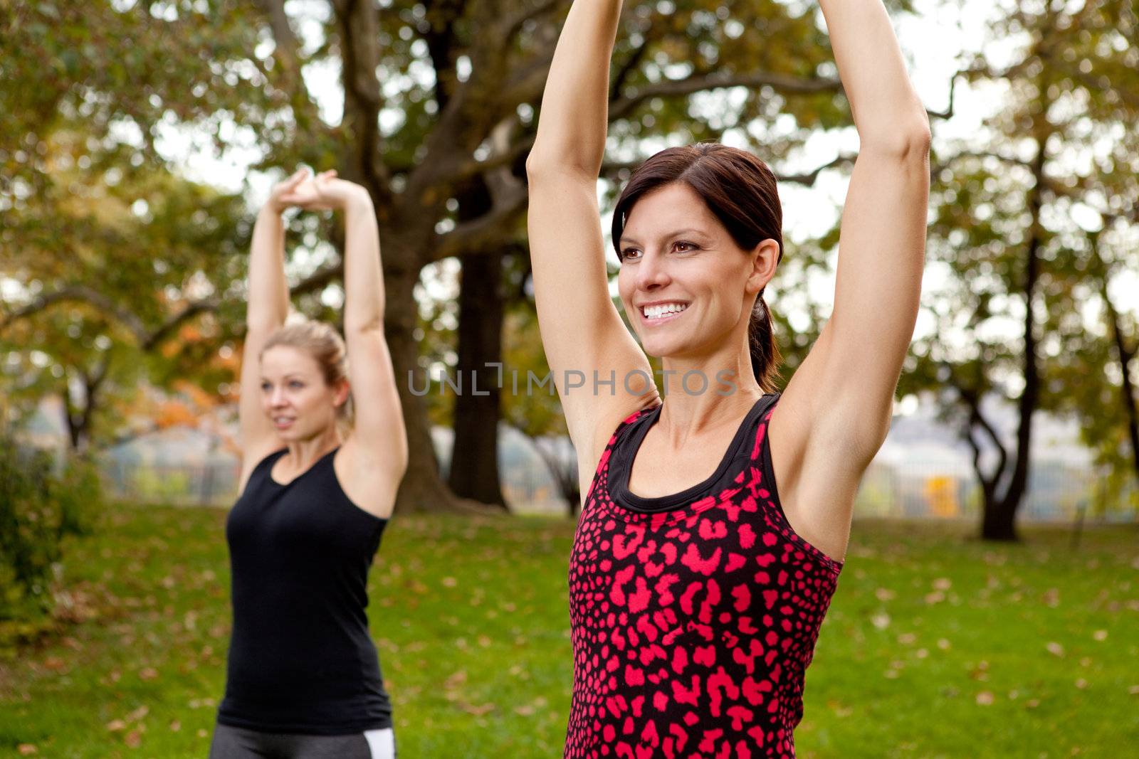 Two women stretching in a park - outdoor exercise