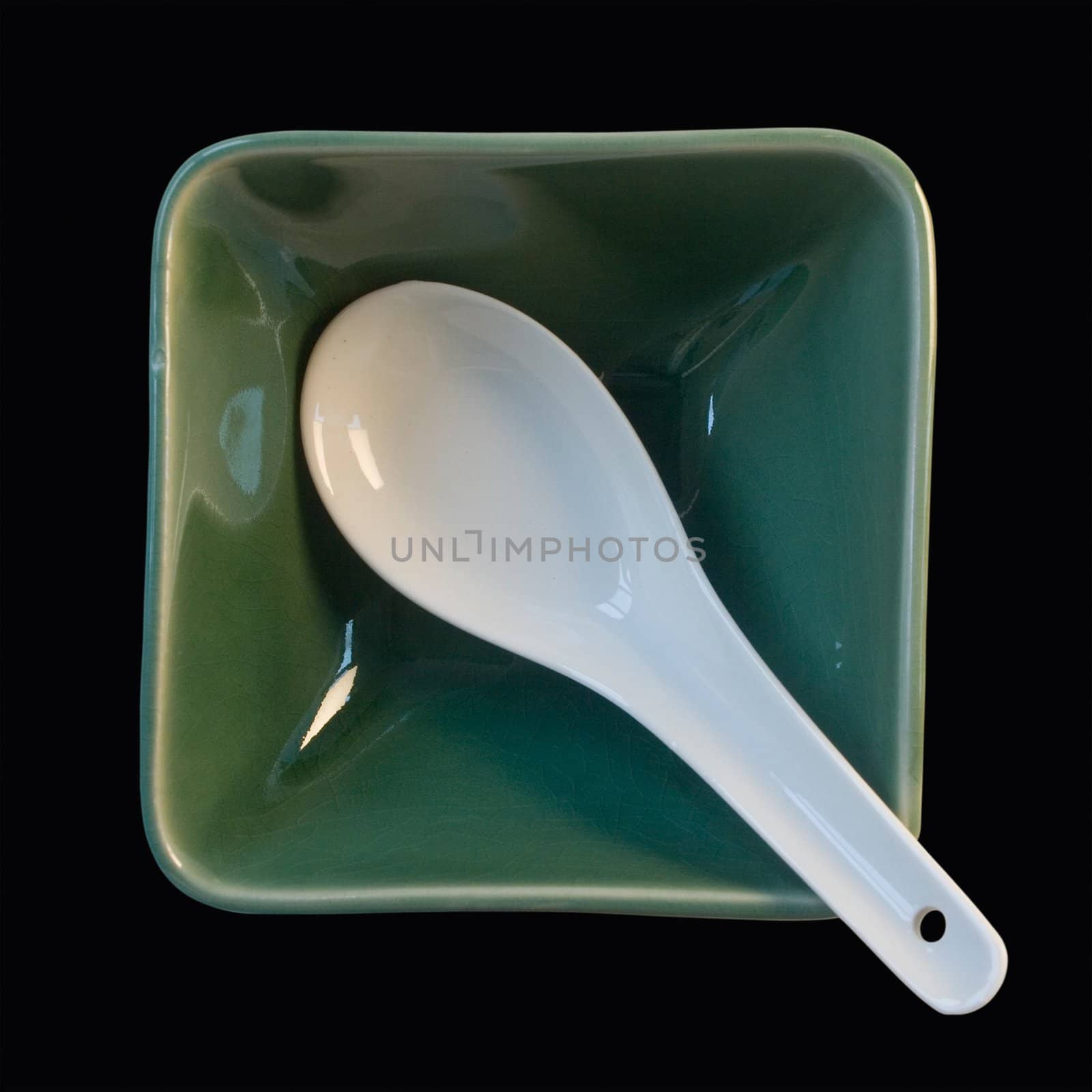 white spoon in green cup isolated on black