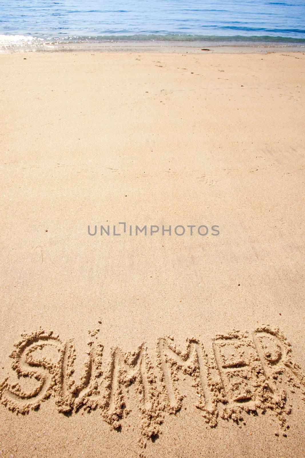 The word summer written in the sand at a beach