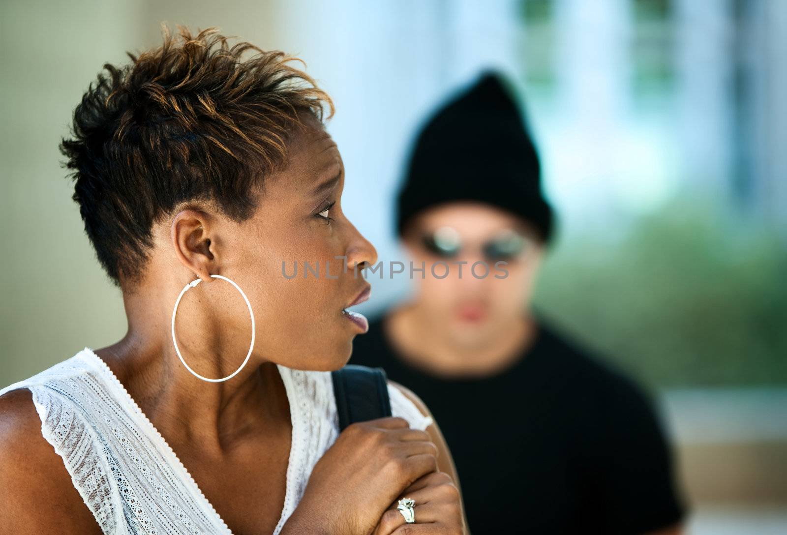 Woman being stalked by criminal in sunglasses and ski hat