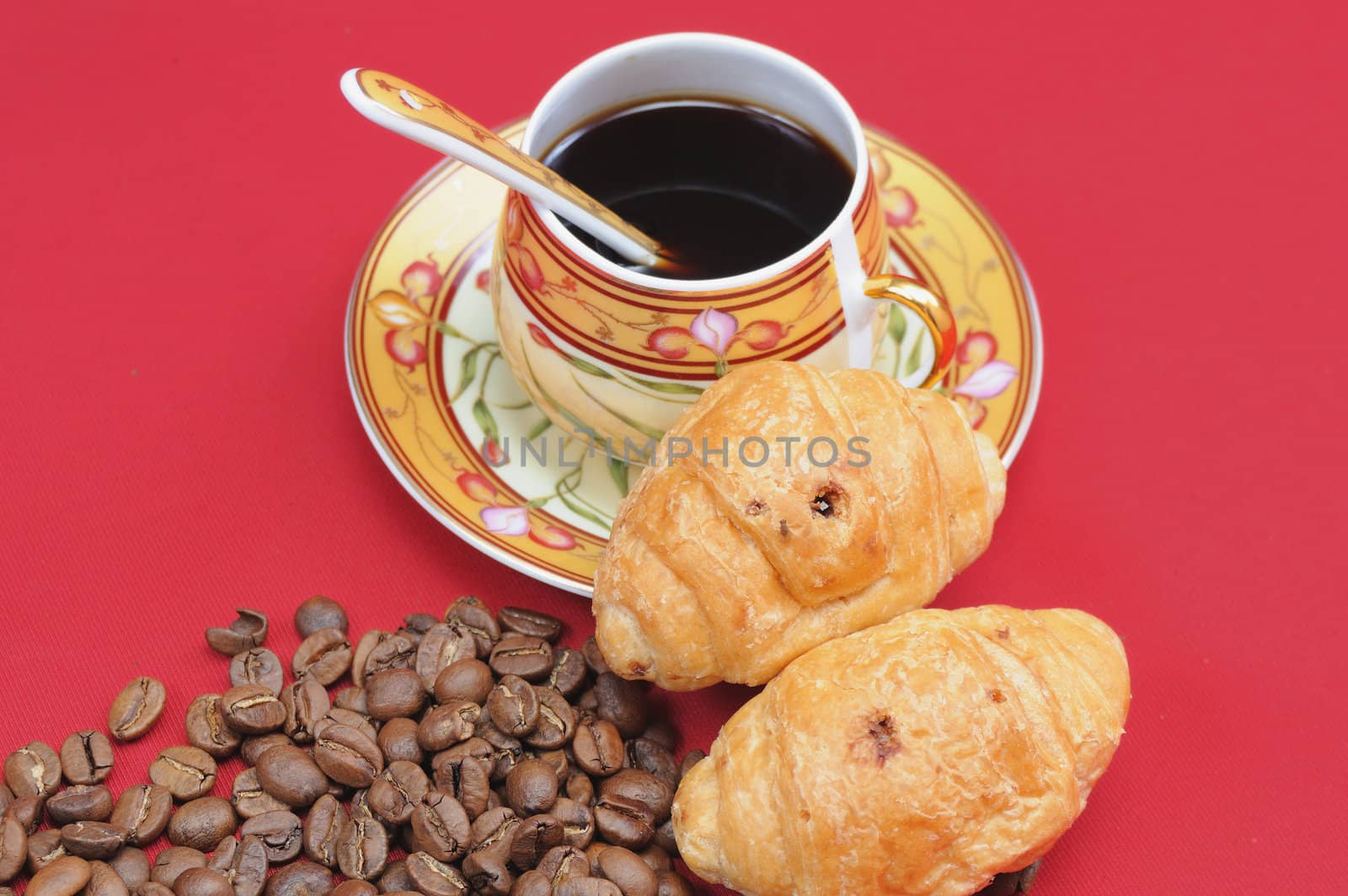 Heap of coffee bean and the cup on a red background