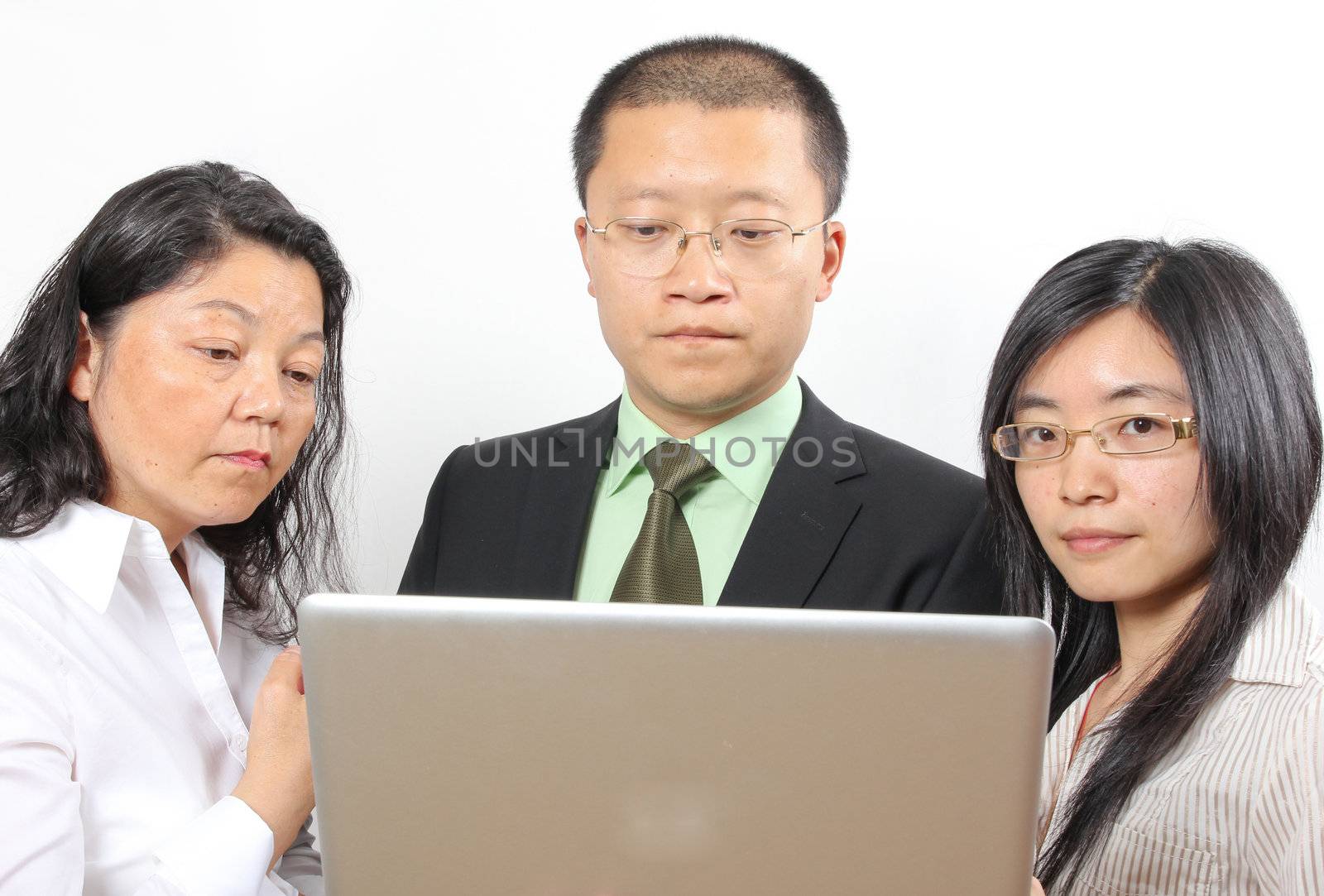 3 chinese businesspeople, standing around a table with a laptop computer