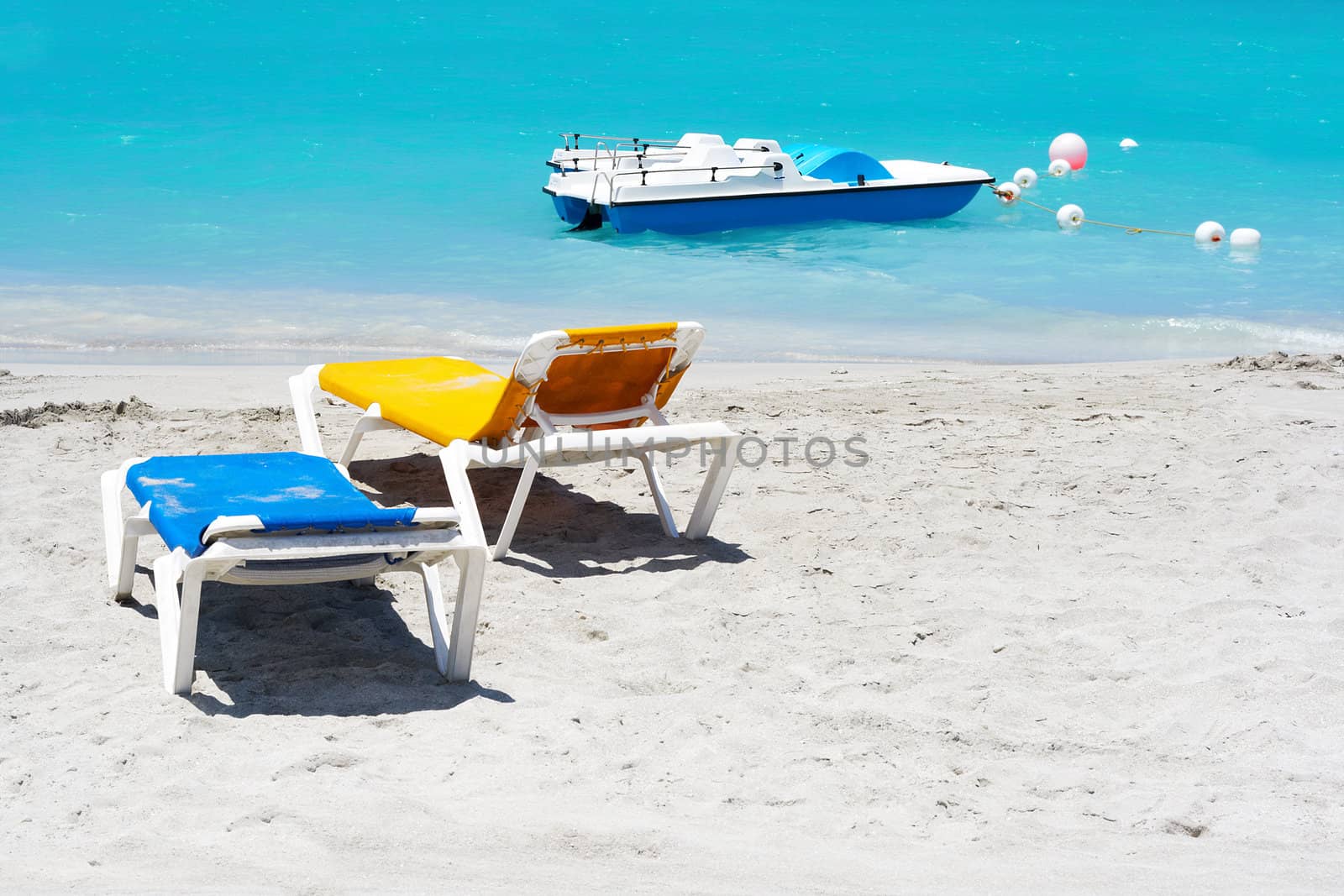 Yellow and blue beach chairs and a water bicycle in the beach