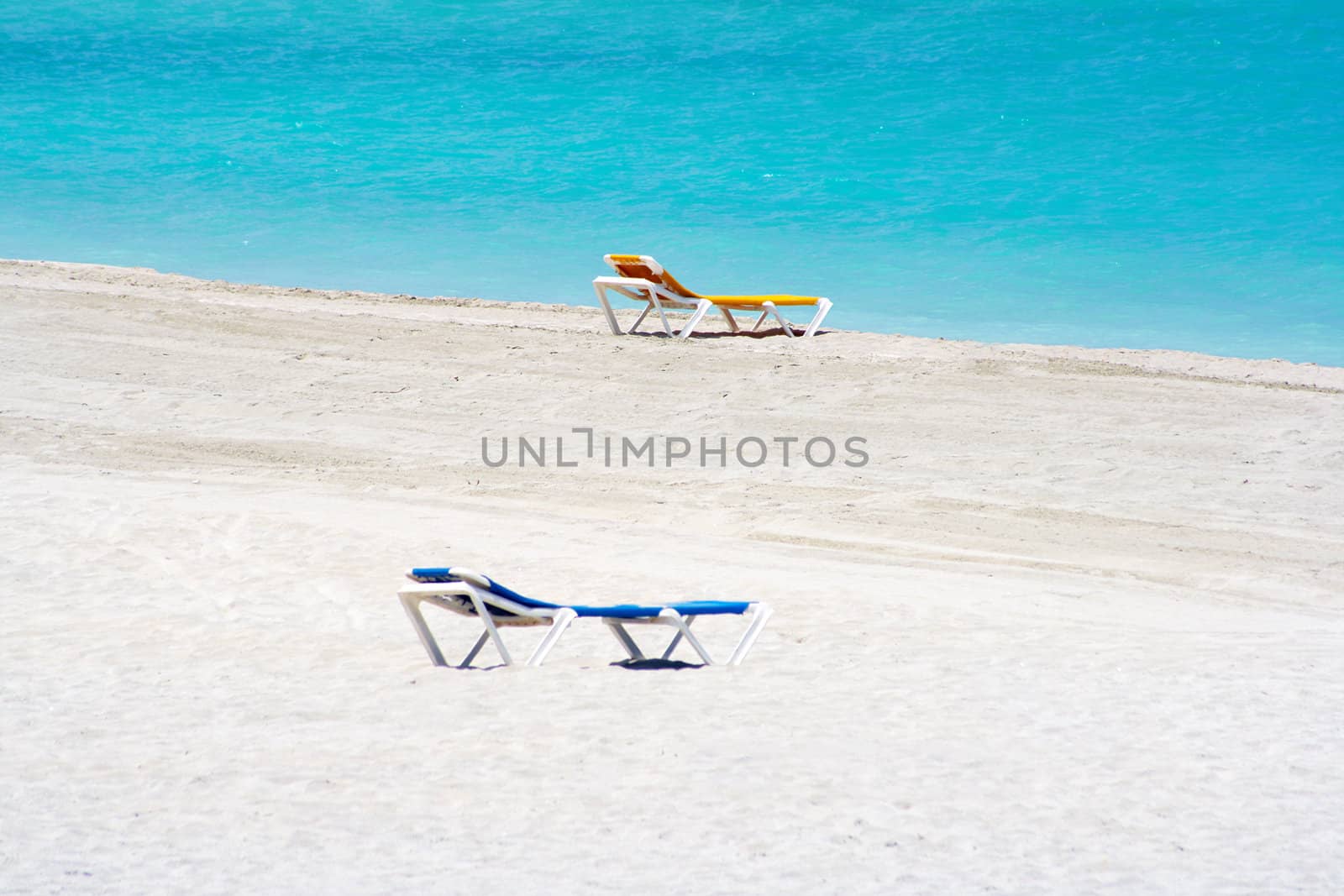 Yellow and blue beach chairs in the sand