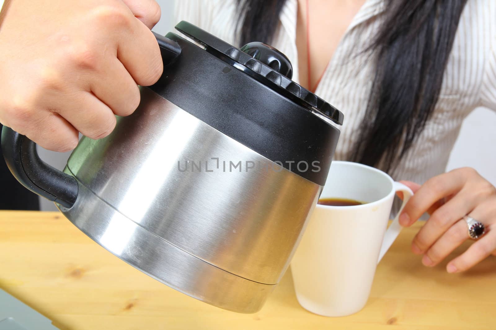 Hand puring coffee to a business woman