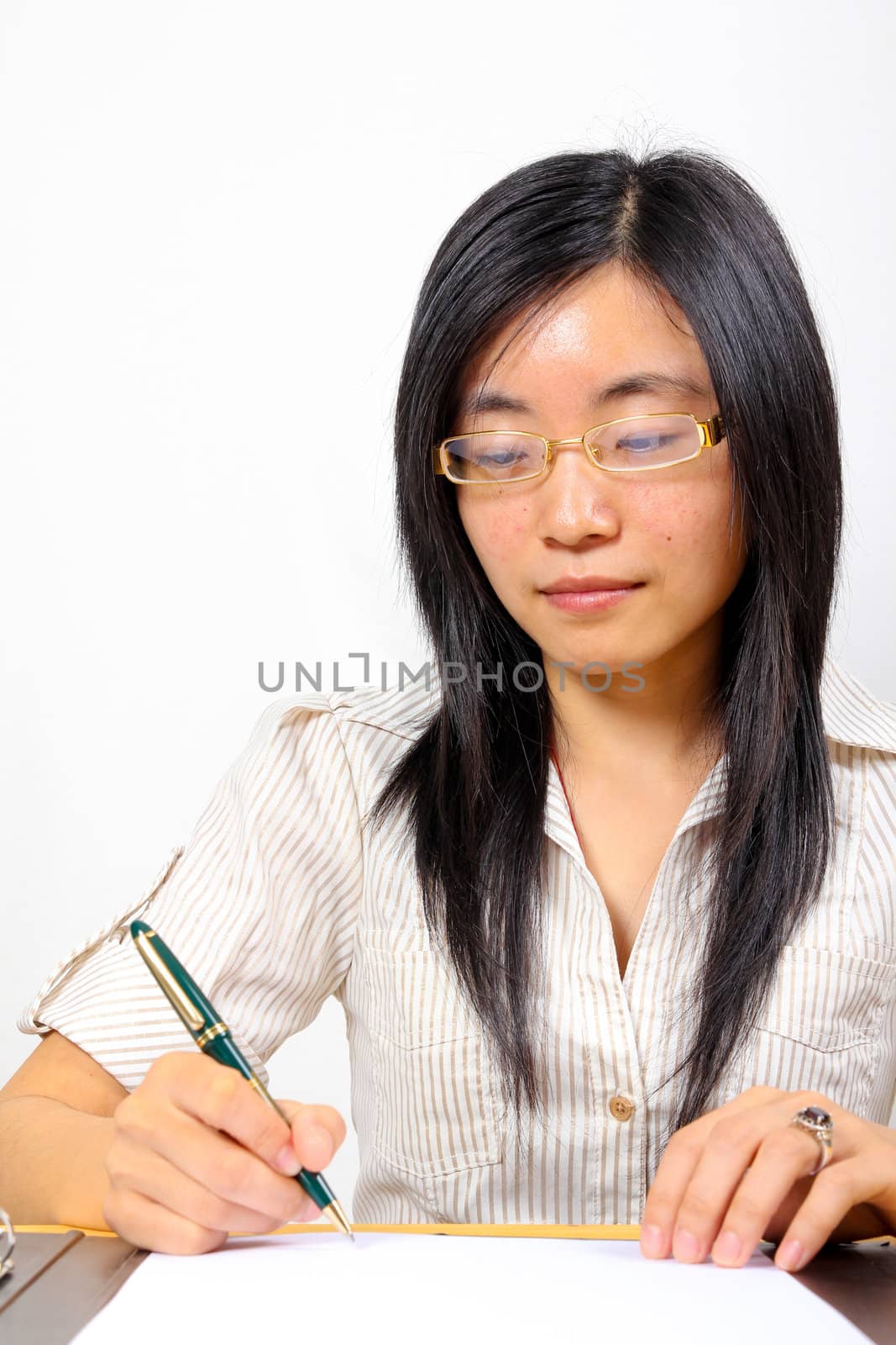 Chinese businesswoman, sitting at desk writing by dotweb