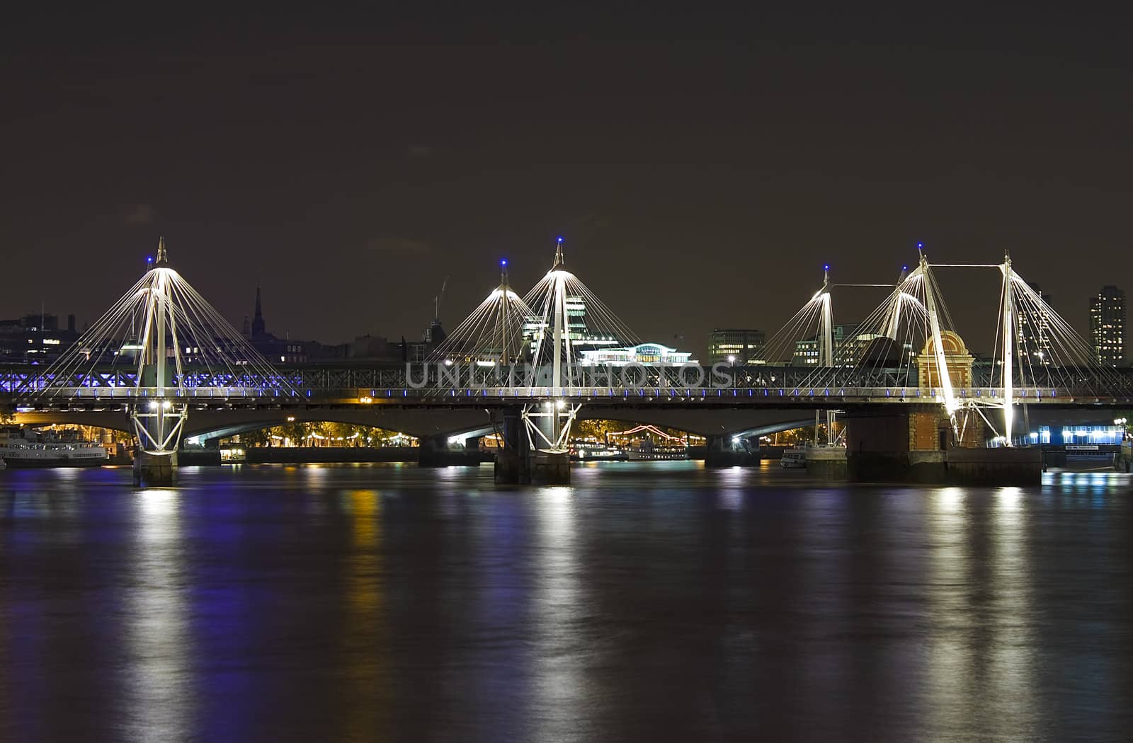 The Jubilee Bridge in London at night with reflection in the river Thames