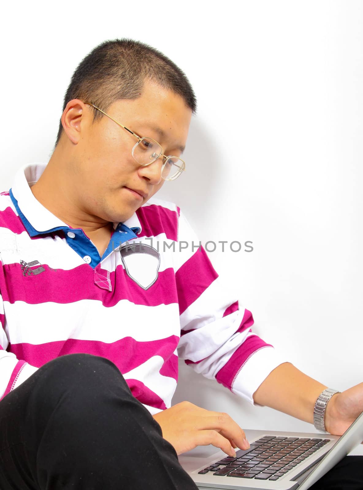 Young chinese man sitting with a laptop by dotweb