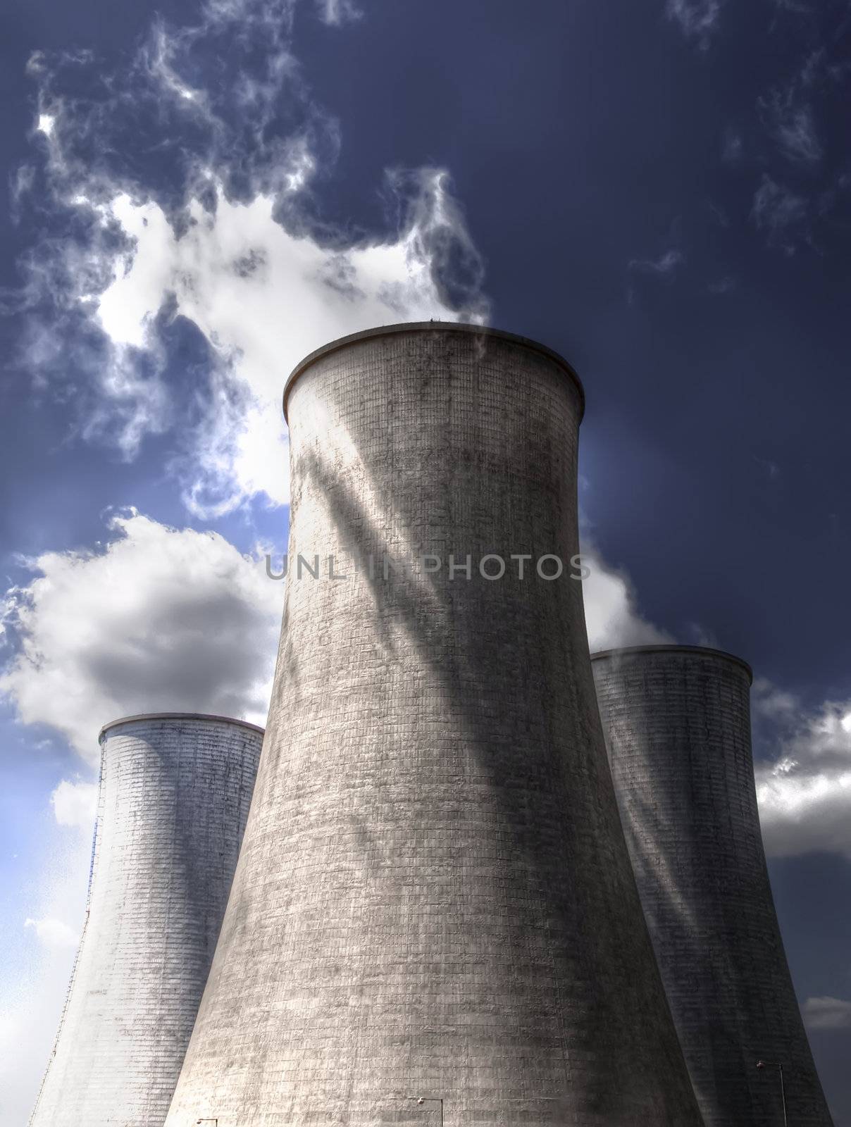 Nuclear cooling towers emitting steam with blue sky