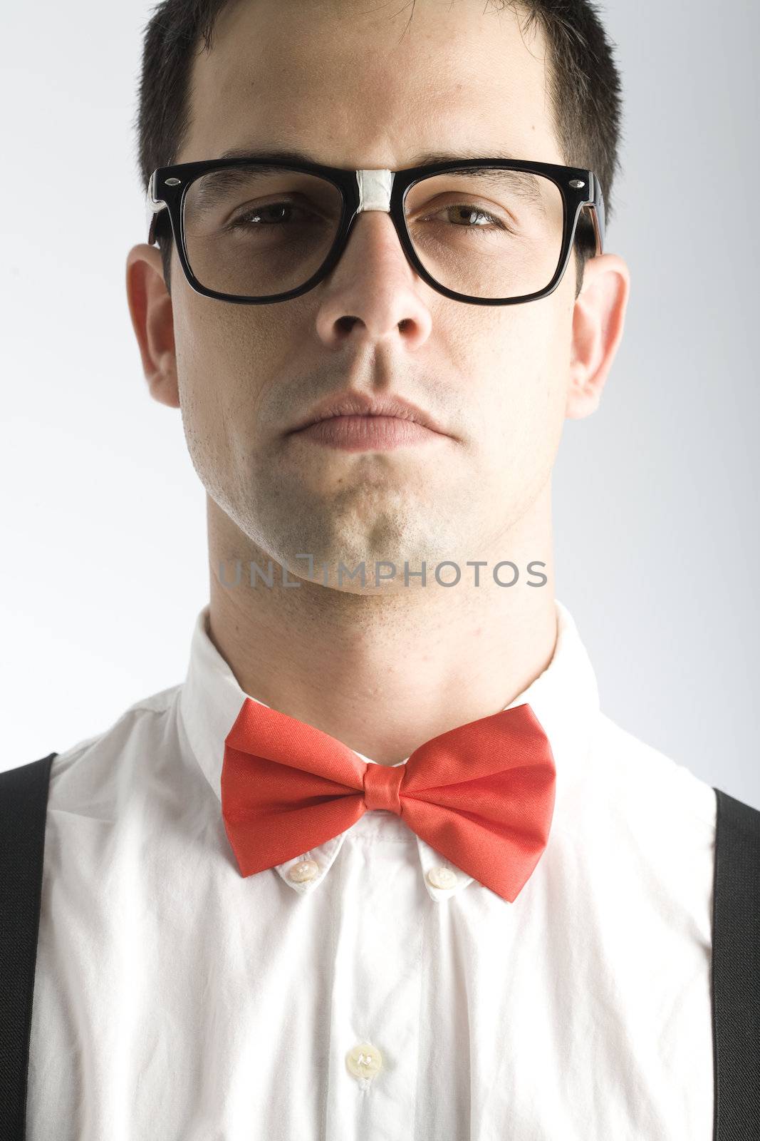 A young, caucasian nerd, close-up, on a light gray background.