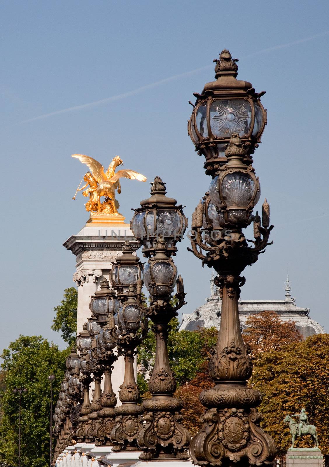 The ornate lampposts on the Pont Alexandre III lead towards one of the golden statues on the bridge