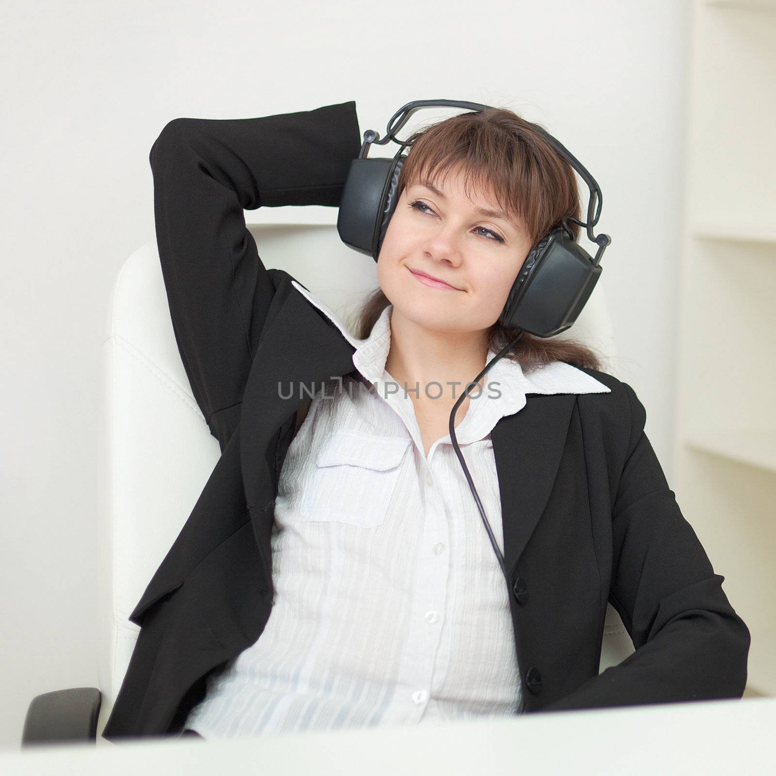 The young girl with the big professional ear-phones on a head sits in an armchair