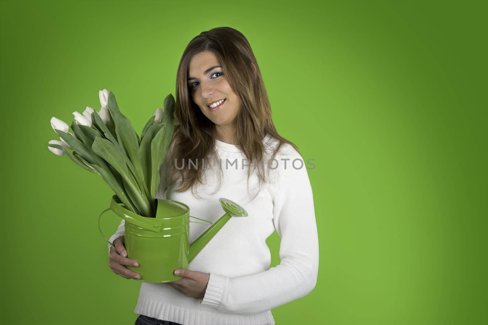 Beautiful woman on a green background with white tulips on a watering can