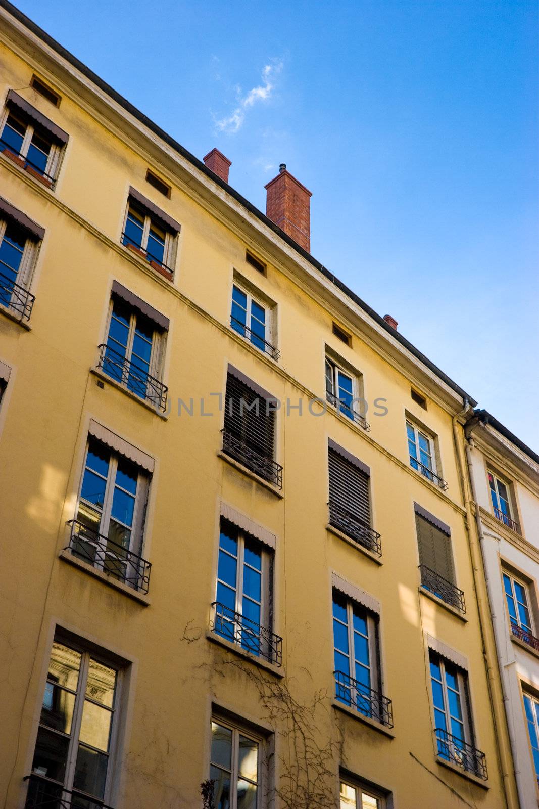Yellow house facade with blue sky reflection in windows