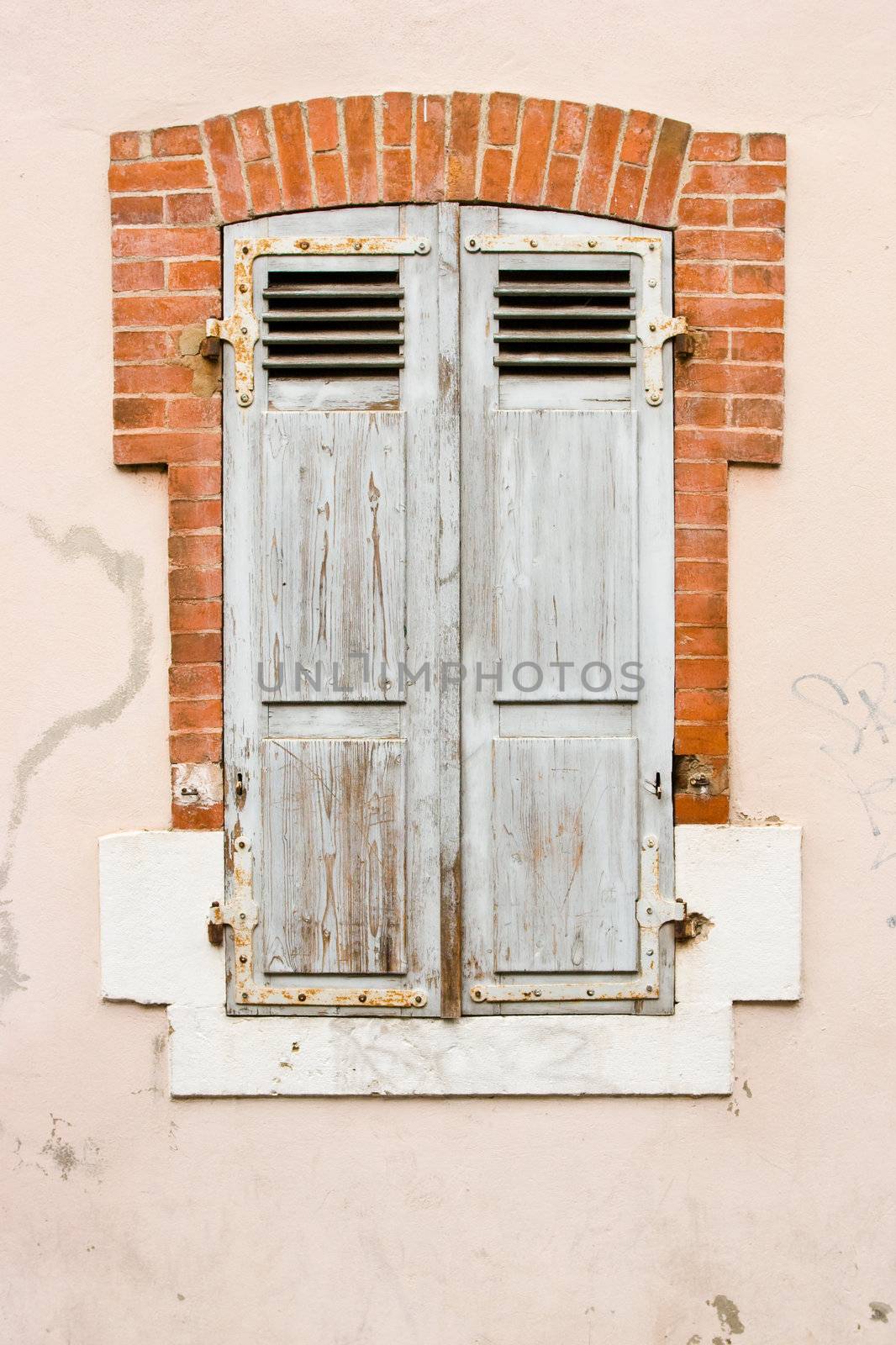 Closed old-fashioned shuttered window in bricky frame