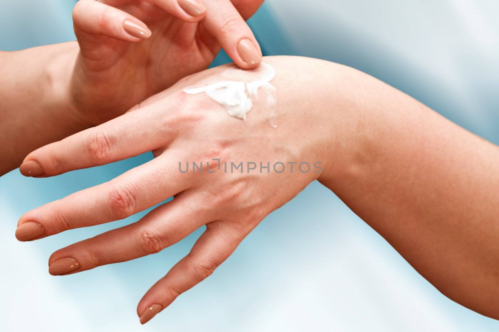 female applying cream to her hands, body care