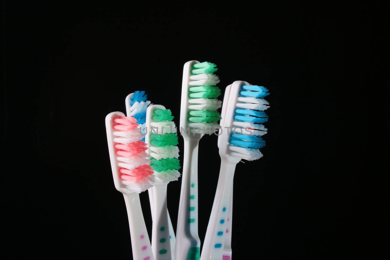 Six new tooth brushes on a black background.