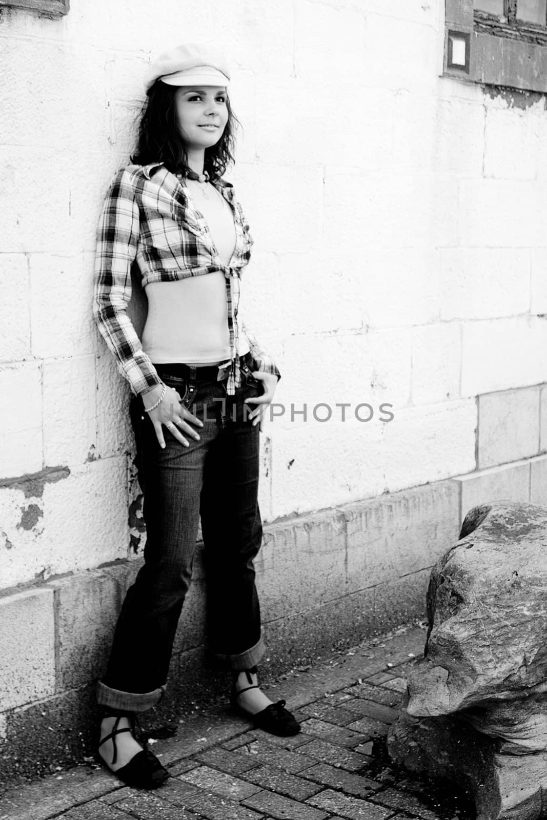 Black and white portrait of a twenty something girl hanging out on a white brick wall