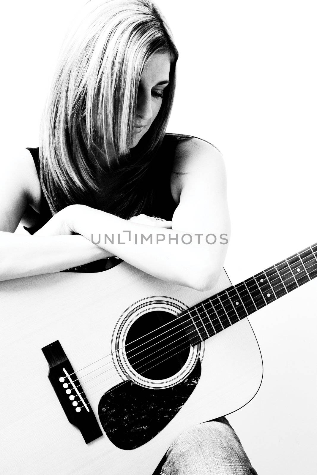 Thirty something women sitting on stule leaning on accoustic guitar looking down