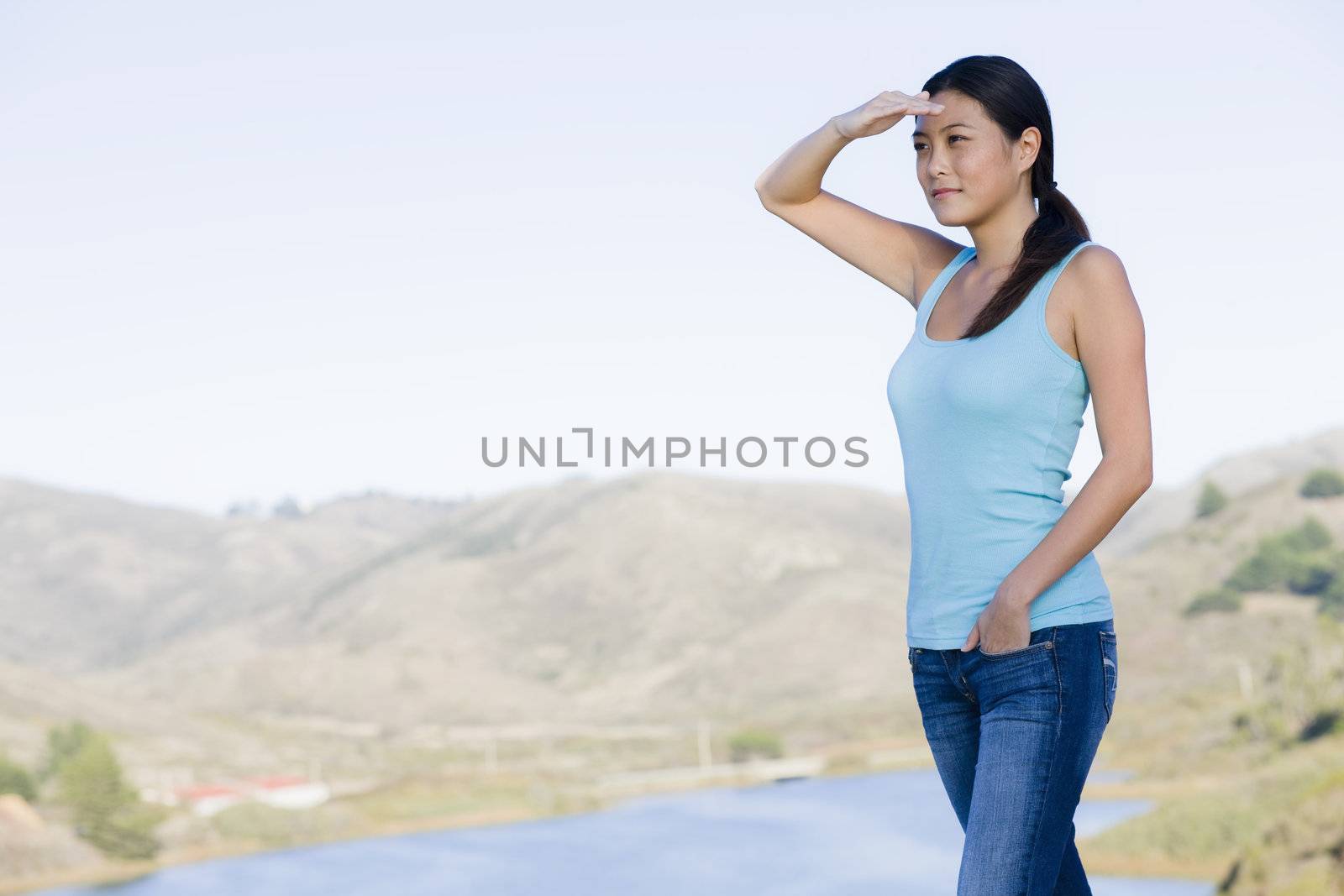 Young Asian Woman Shielding Eyes Standing in Landscape