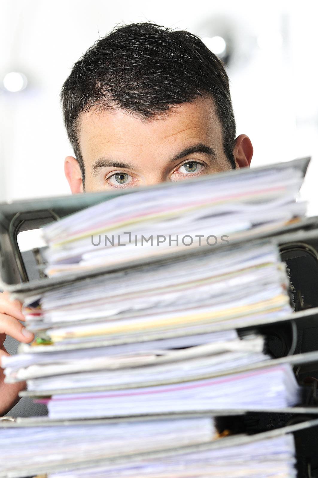 busy man hiding behind a stack of files