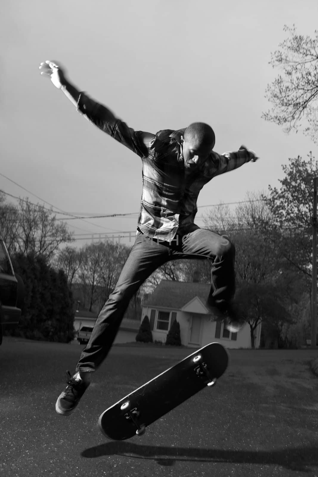 A skateboarder performing jumps or ollies on asphalt.  Slight motion blur showing the movement on the arms and legs.