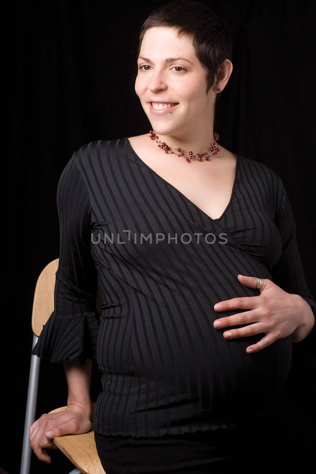 Sitting portrait of a late twenty pregnant women giving a side glance to the left